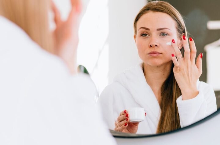 Women sit in front of mirrior and apply best retinol cream